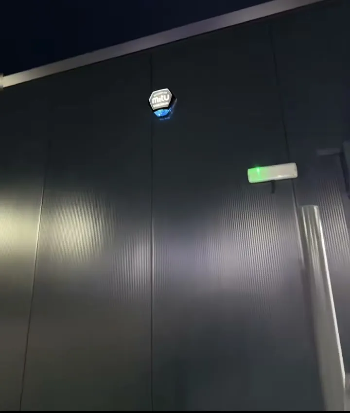 The finished siren cover lit up at night against the shop's dark cladding