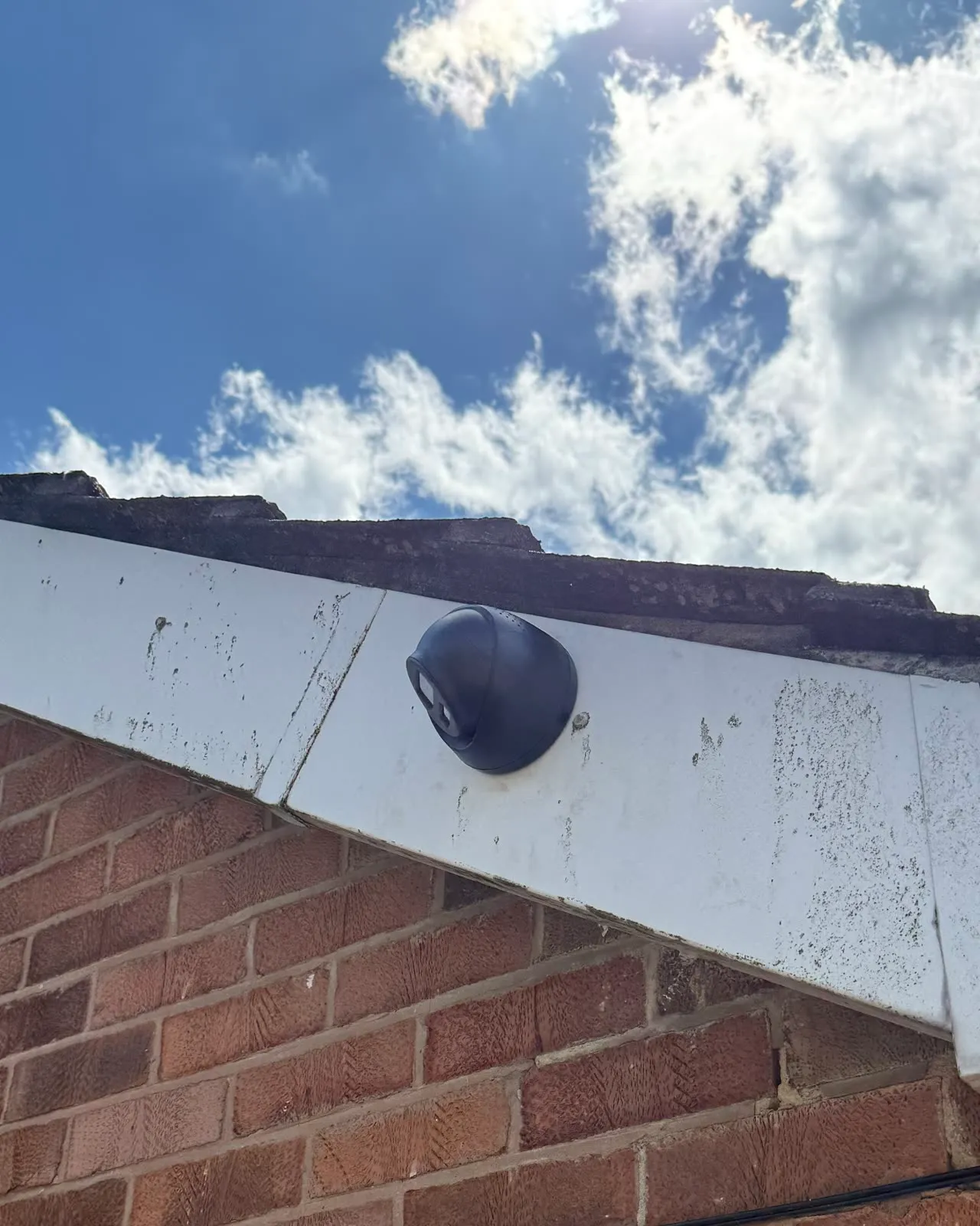 The finished camera: a Hikvision turret sat flush on a white bargeboard above red brick, no cable in shot