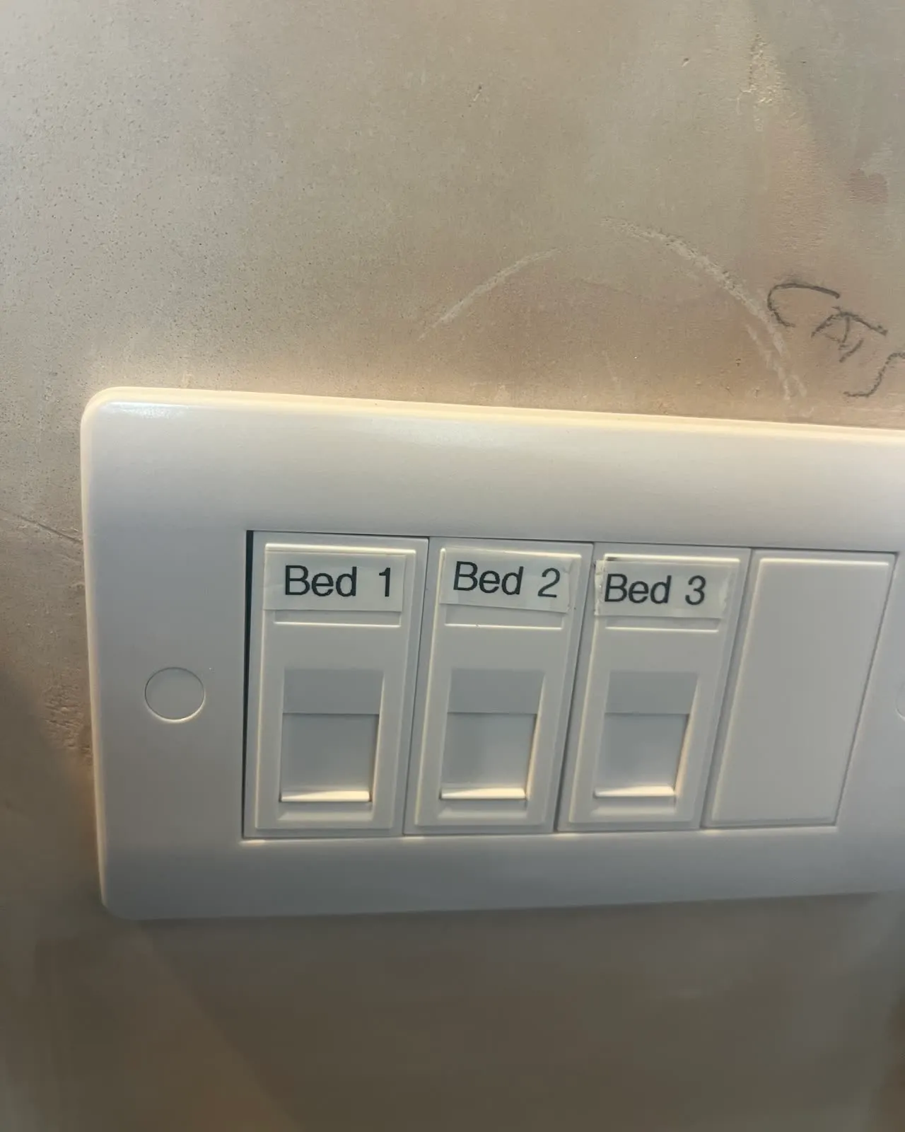 A white three-gang data faceplate on a freshly plastered wall, its ports labelled Bed 1, Bed 2 and Bed 3