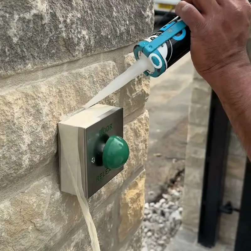 Sealing round a stainless exit button set into the stone gate pillar
