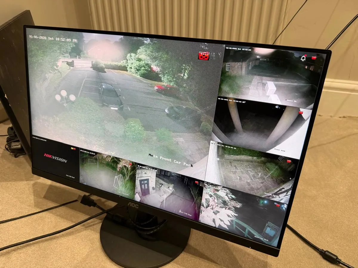 A monitor showing four live camera feeds from a house at night