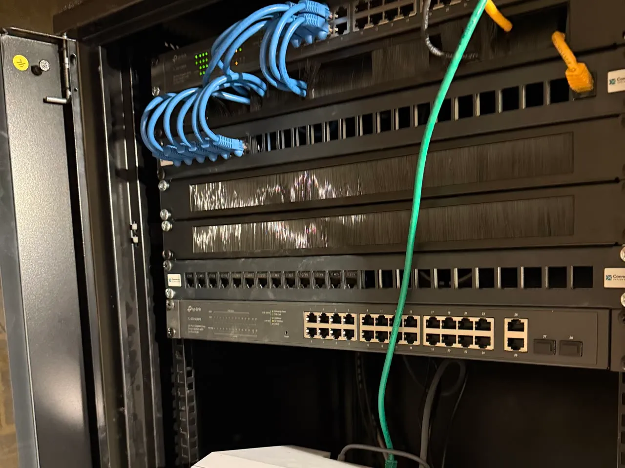 Inside the finished data cabinet: patch panel with blue leads, a network switch below it, everything labelled