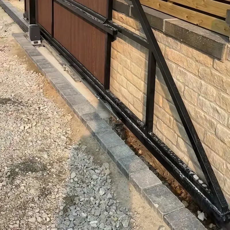 The Nice motor at the foot of a sliding gate, with the rack and track along the base